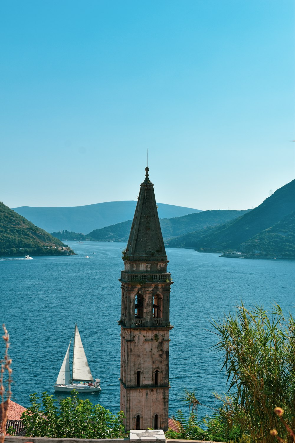 a tower with a steeple by a body of water