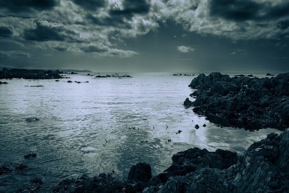 a rocky beach with a body of water in the background