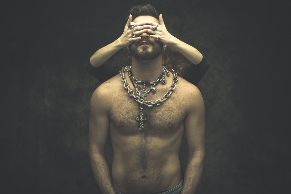 a woman with a chain on her neck and a hand on her face