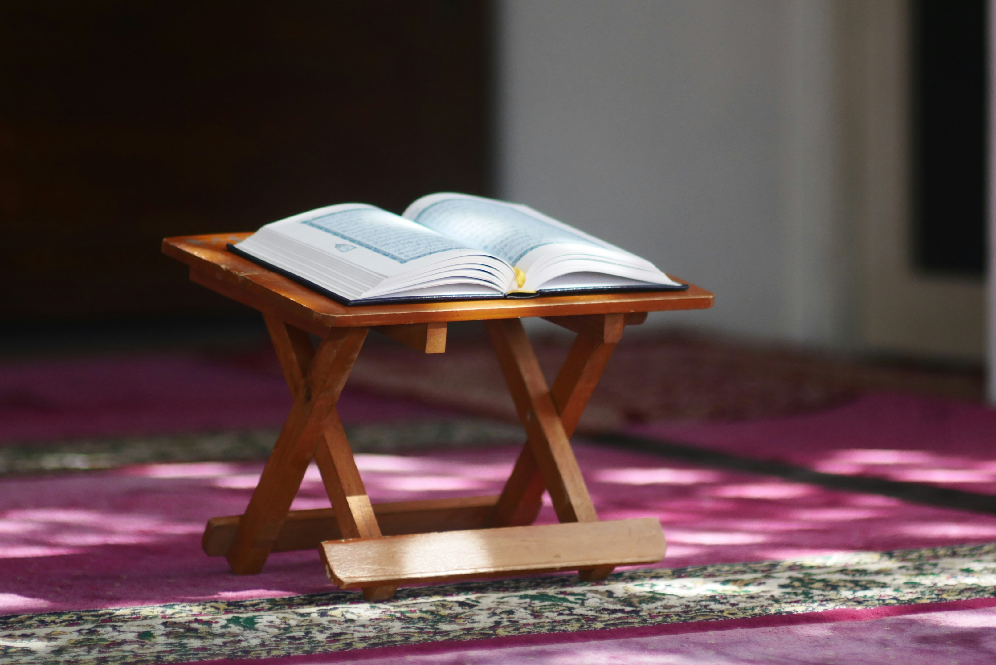 An open religious book rests on a wooden stand.