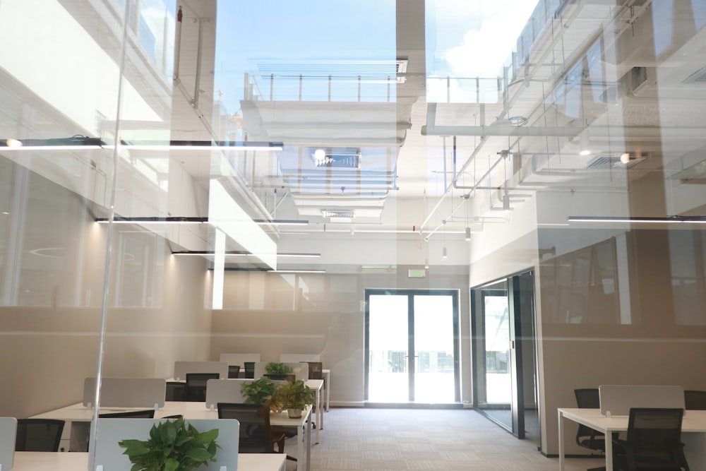 a room with glass walls and a table with chairs and plants