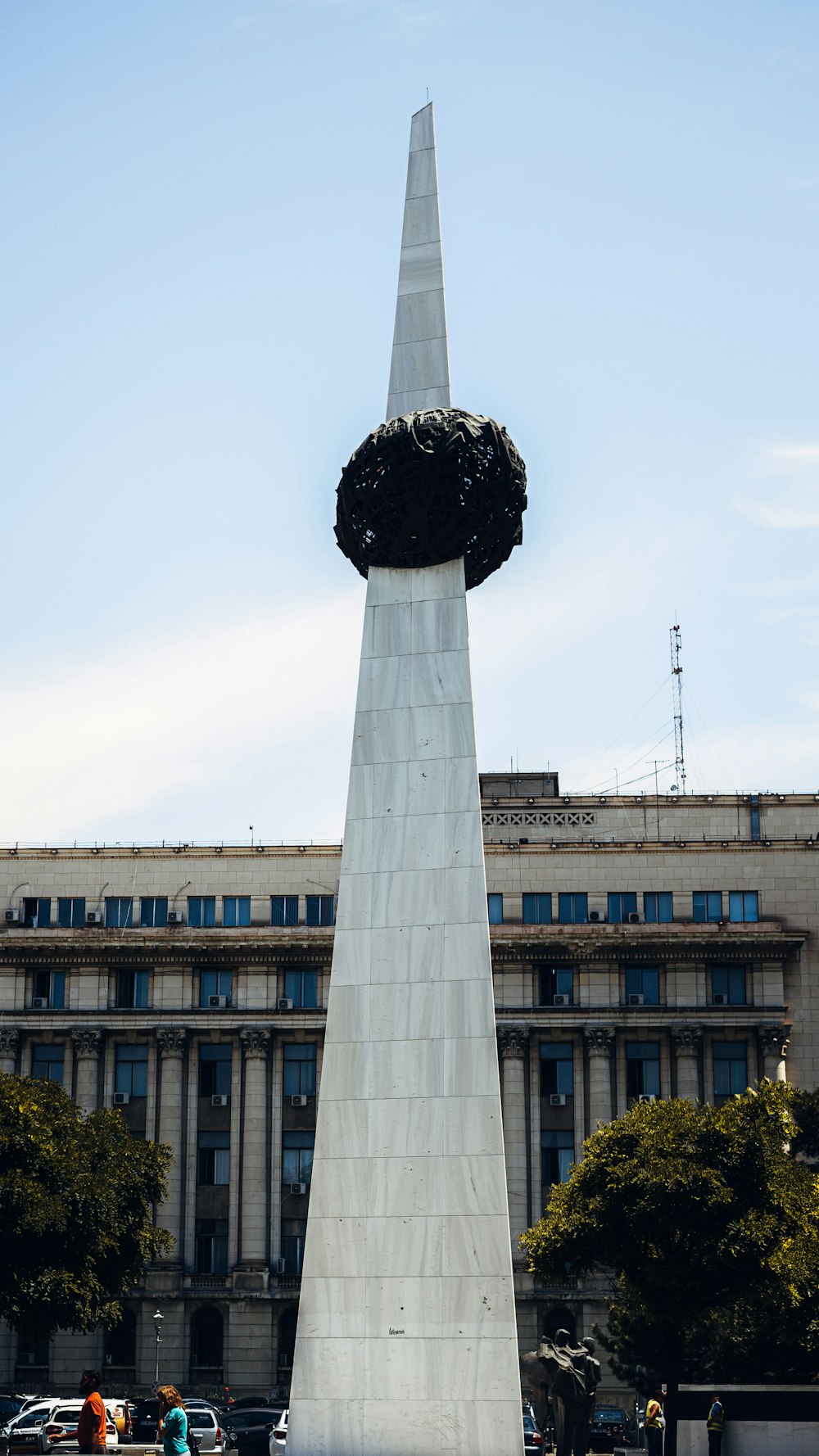 a tall white tower with a statue in front of it with Euromast in the background