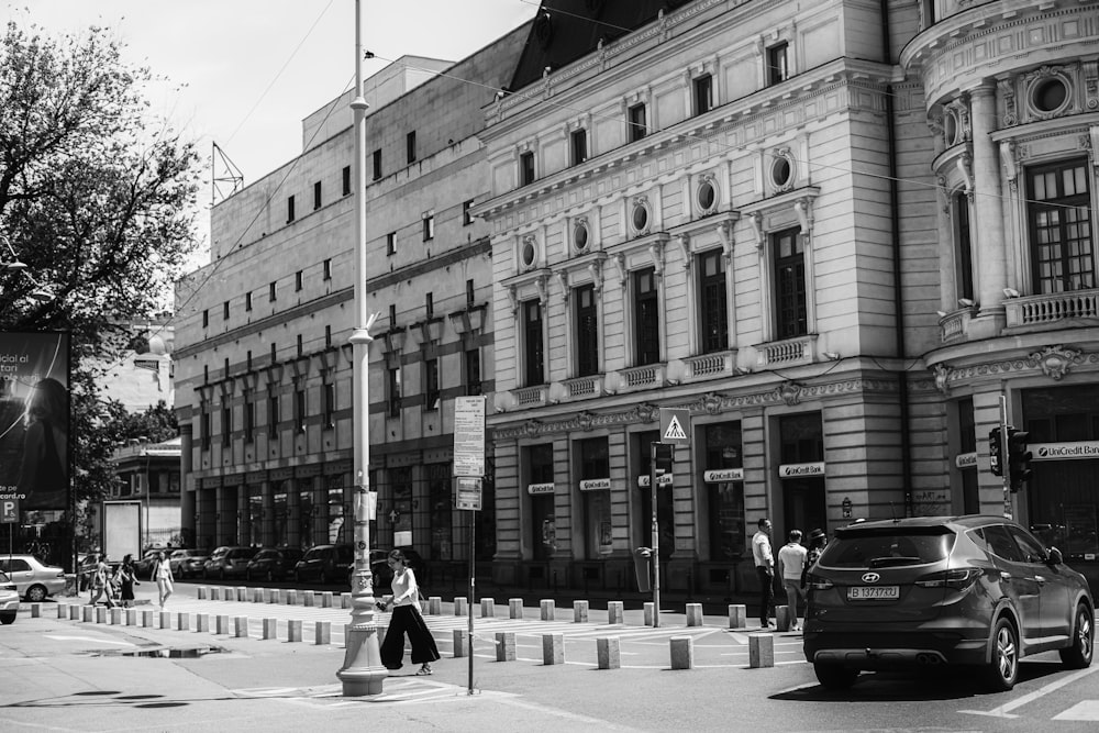 Una foto en blanco y negro de una esquina de la calle con un coche y gente