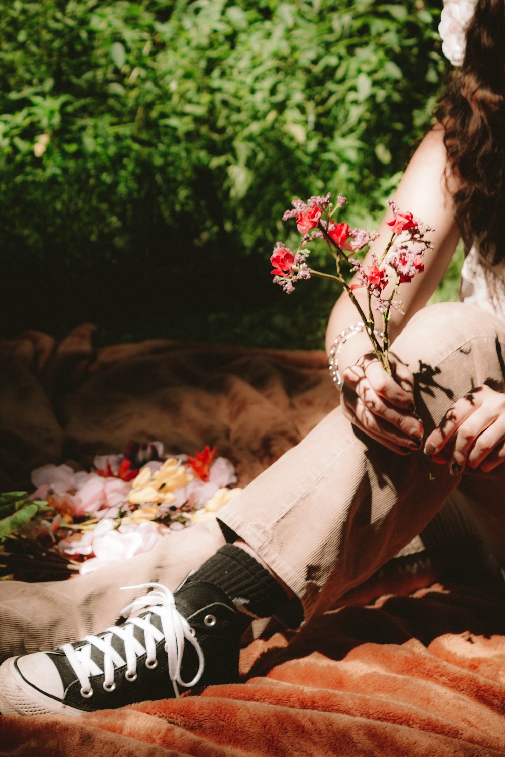 a woman sitting on a blanket with flowers in her lap