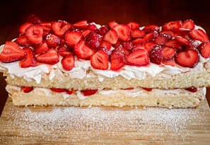 A delicious slice of tres leches cake topped with whipped cream and strawberries.