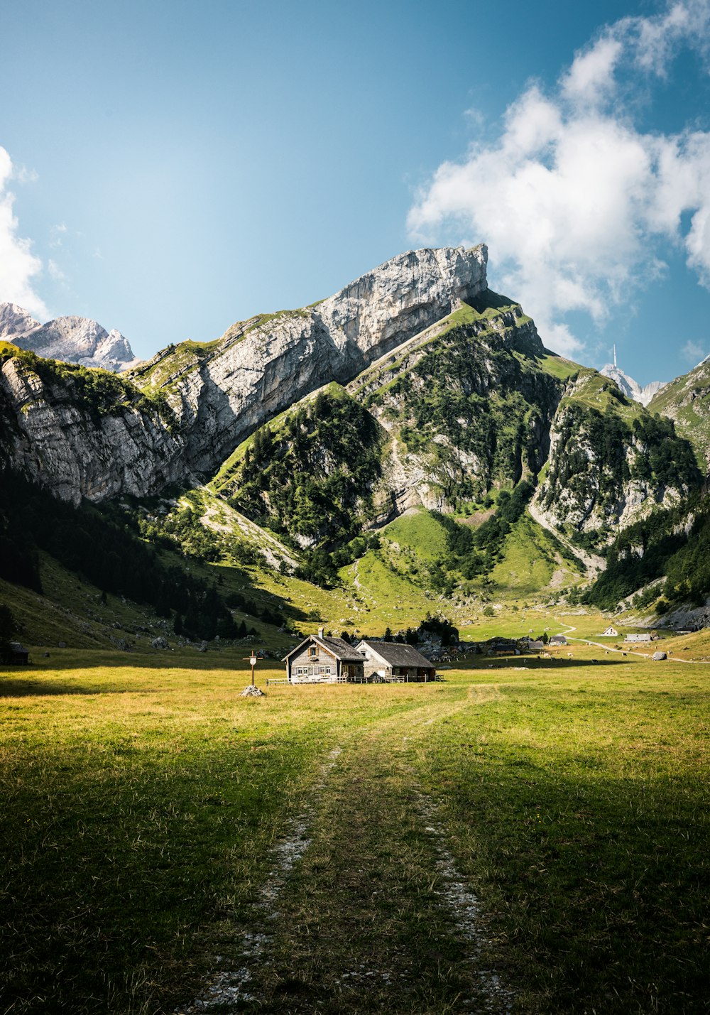 Una casa en un campo cubierto de hierba con montañas al fondo