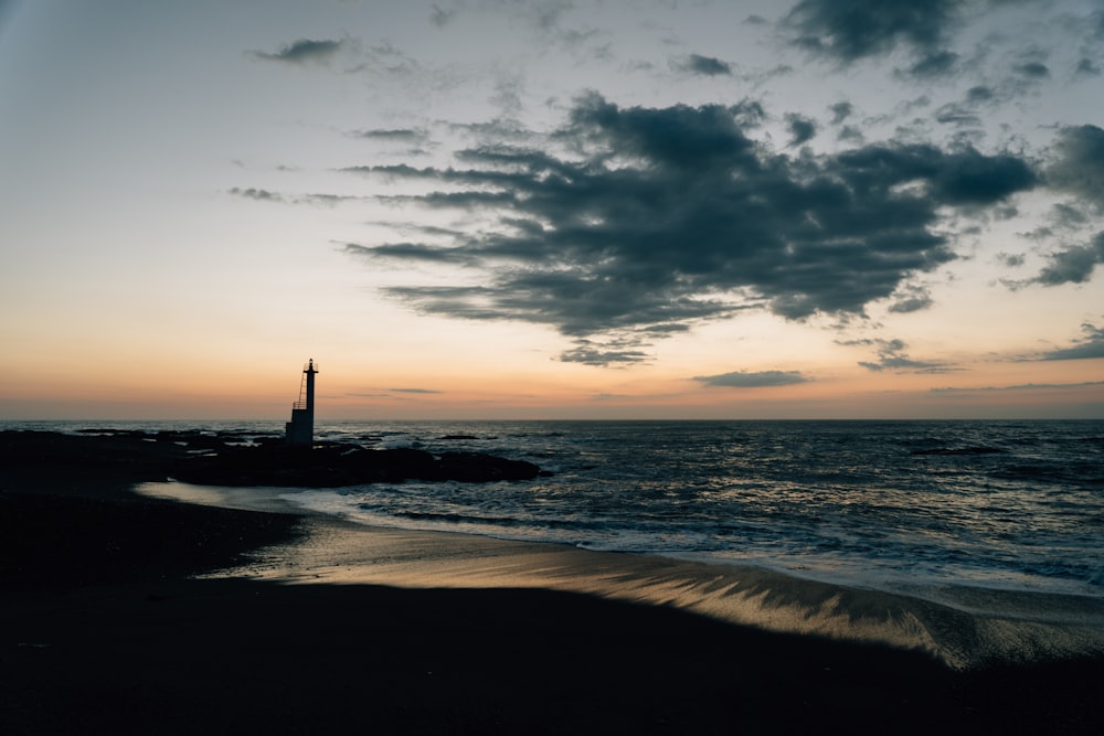 a beach with a lighthouse in the distance