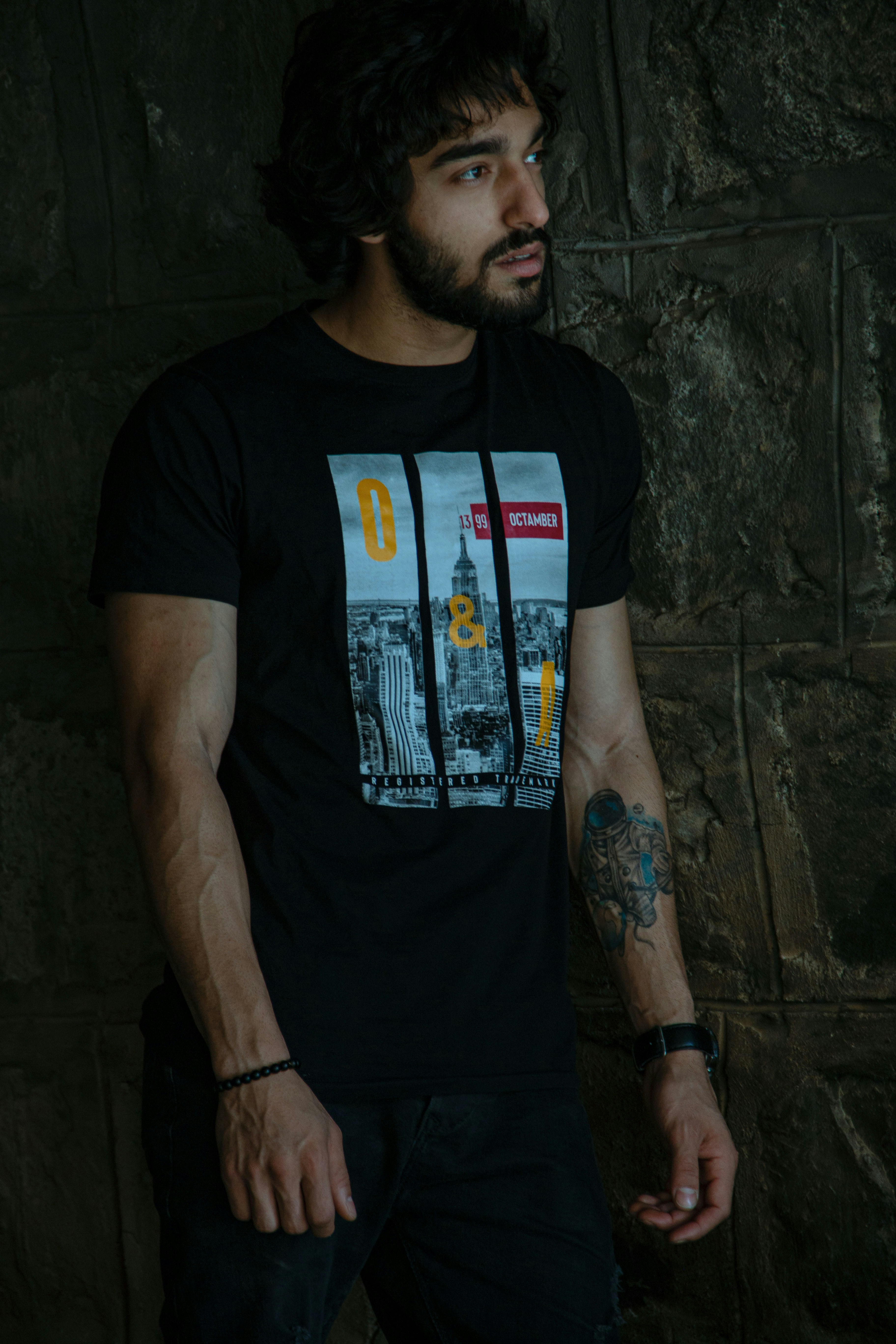 Person wearing dark graphic t-shirt in urban street setting with city background
