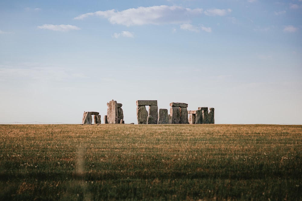 a field of grass with stone structures in the distance