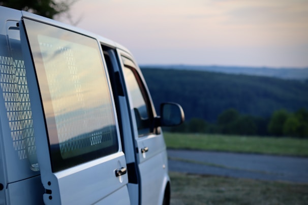 A comfortable passenger van parked by a scenic roadside at sunset.
