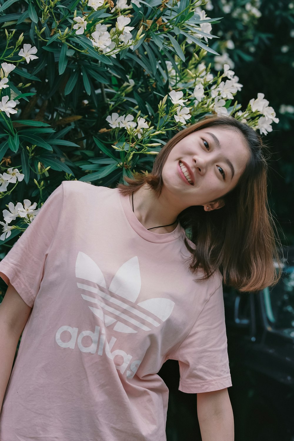 a person smiling in front of a bush of white flowers