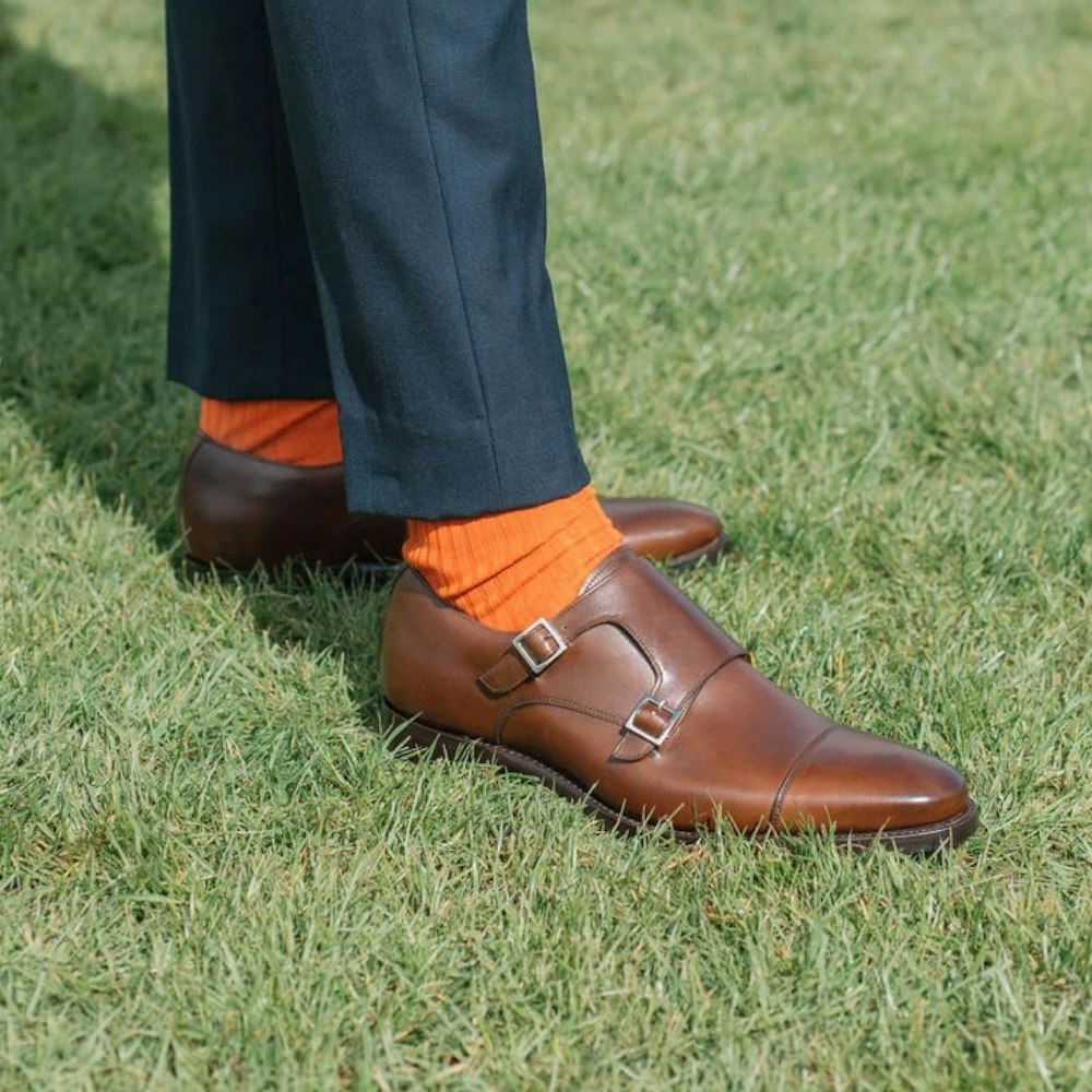 a person's feet in brown boots on grass