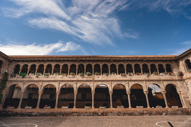 The curved Inca wall and colonial church above the Qorikancha in Cusco at golden hour