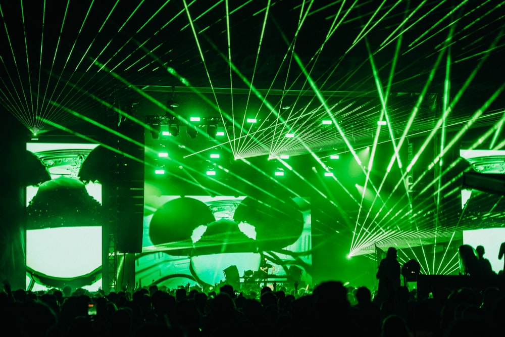 a crowd of people in front of a stage with green lights
