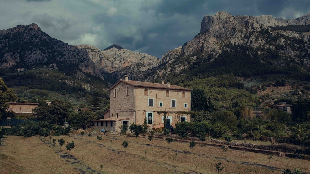 a house in the middle of a field with mountains in the background