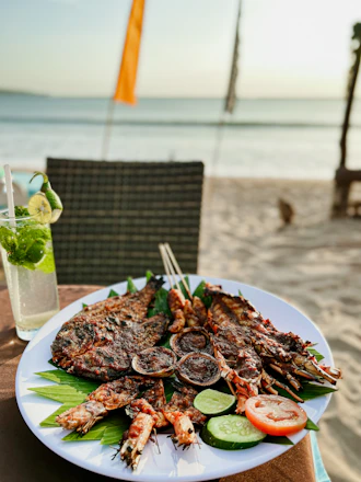 A vibrant platter of grilled seafood with tropical herbs on a bamboo table by the seaside.