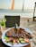 A happy customer enjoying a vibrant plate of grilled seafood at a tropical restaurant.