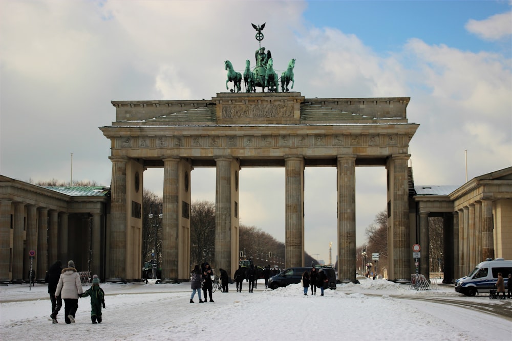 a large stone arch with a statue of a person on a horse with Brandenburg Gate in the background