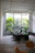 An architect reviewing blueprints in a bright office filled with plants and natural light.