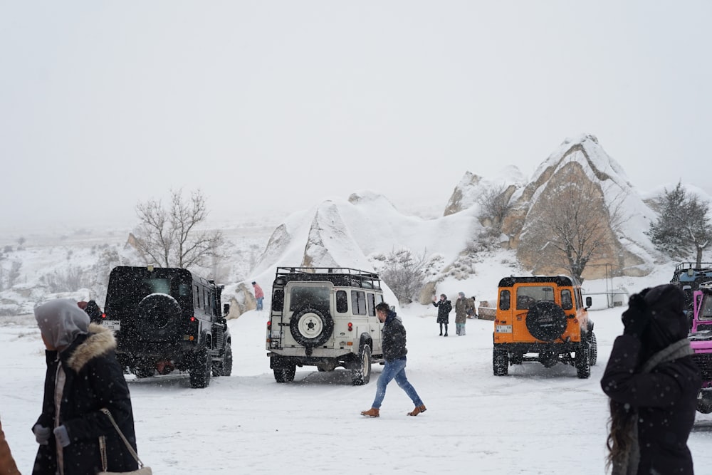a group of people walking in the snow next to a group of vehicles