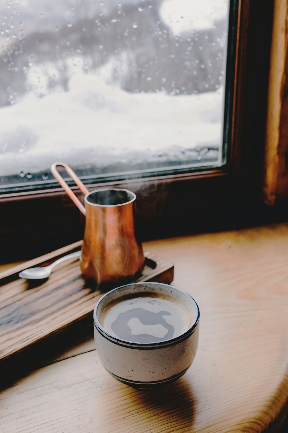 a cup of coffee and a teapot on a table