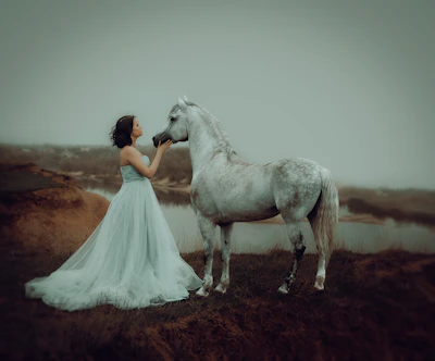 a person in a white dress and a white horse on a dirt road