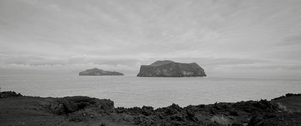 a rocky beach with a couple of large islands in the distance