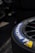 A close-up view of a Michelin tire with part of the brand logo and name clearly visible. The tire appears to be attached to a wheel with visible spokes, set against a dark and slightly blurred background.