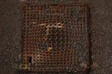Industrial setting showing a heavy-duty manhole cover with bolts securing it.