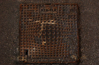 A technician inspecting a yellow FRP manhole cover on a busy street.