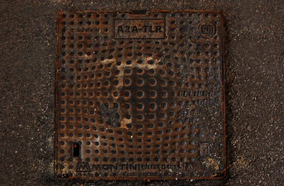 Industrial setting showing a heavy-duty manhole cover with bolts securing it.