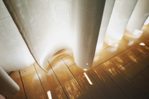 Natural light pouring through sheer curtains onto a polished stone surface with a softly glowing candle.