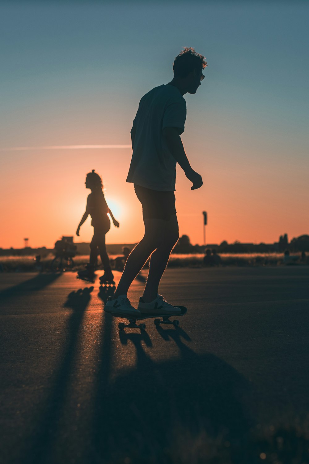 a man and a woman walking on a road at sunset