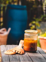 Close-up of golden ghee in a glass jar with a wooden spoon resting beside it.