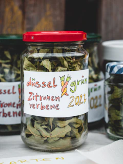 A close-up of vibrant, hand-blended herbal teas in glass jars with handwritten labels.