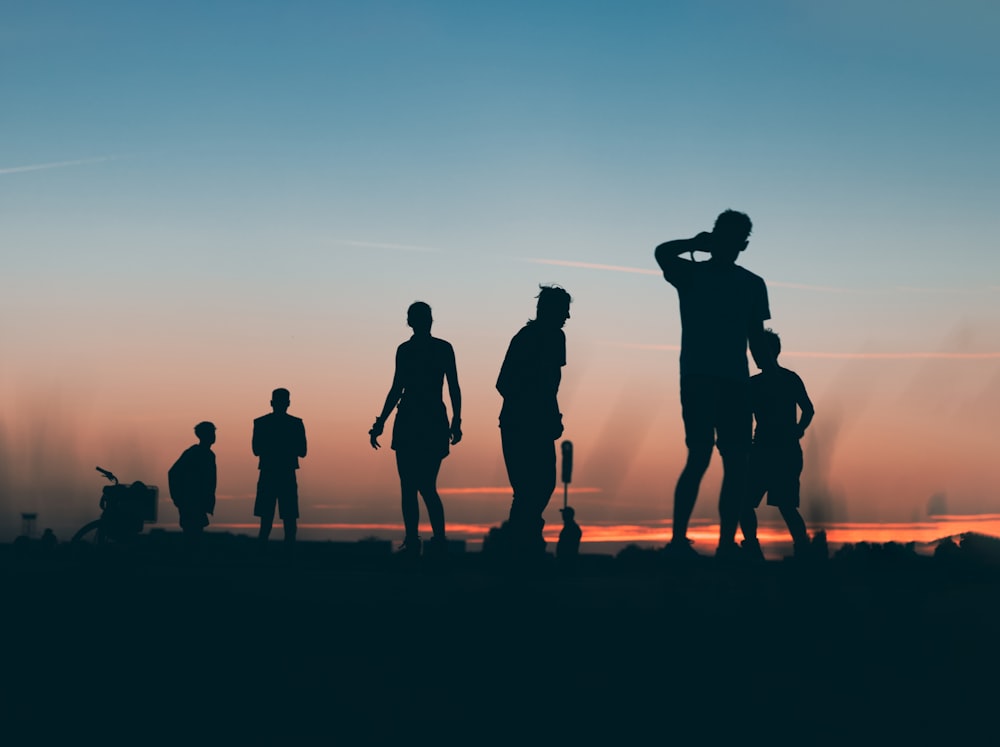 a group of people standing on a beach at sunset