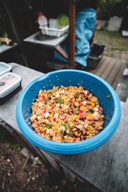 A colorful bowl of fresh mixed vegetables and grains on a rustic table.