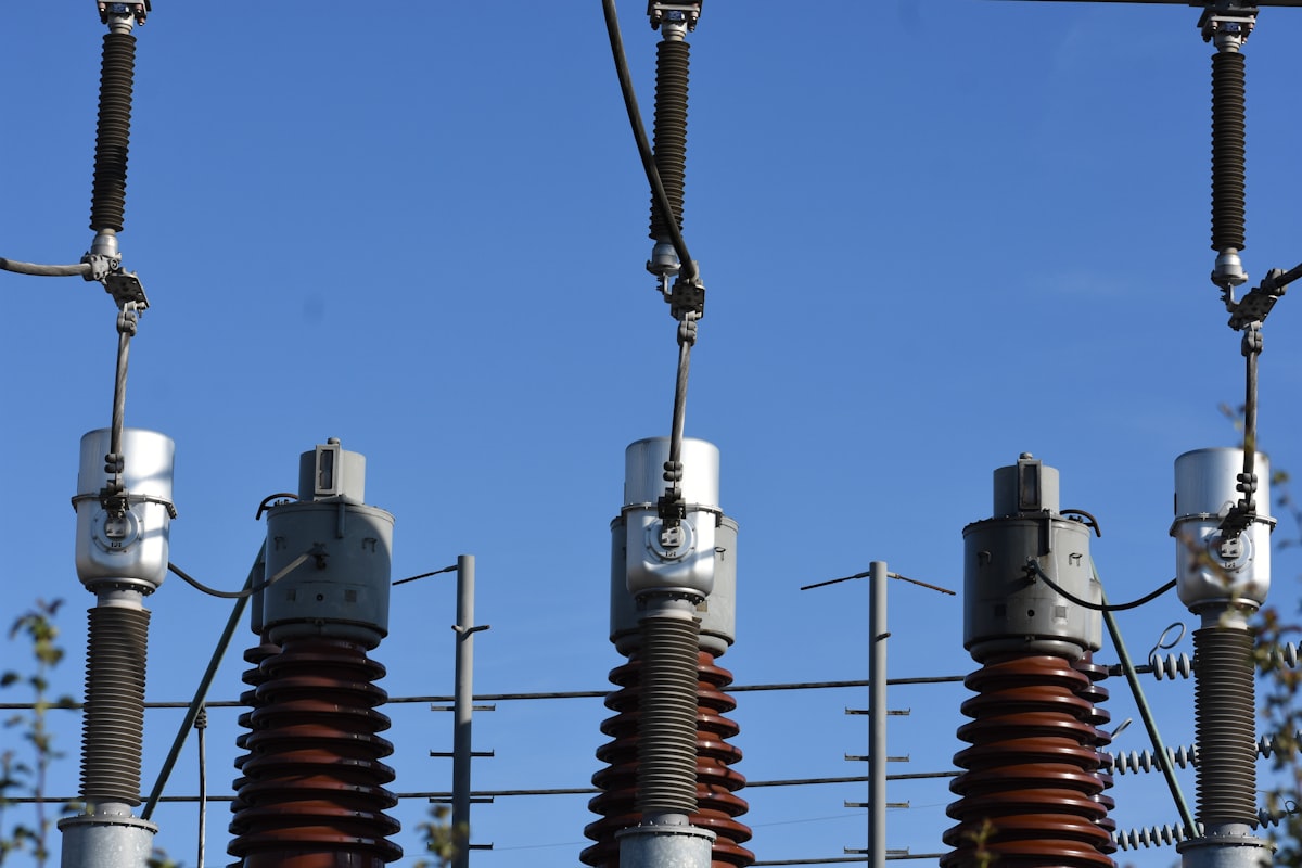 High-voltage power transmission towers against the sky representing the physical infrastructure powering the AI economy