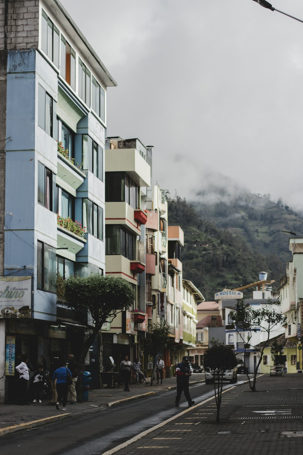 a street with buildings and people on it with a mountain in the background
