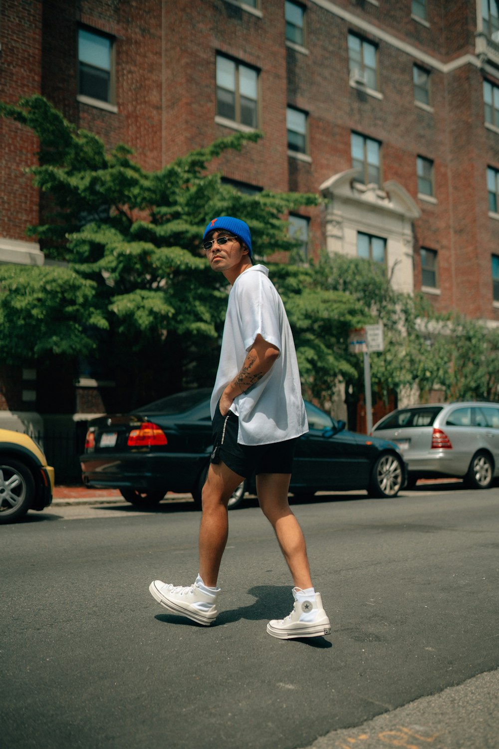 Un uomo con un cappello blu e pantaloncini che cammina per strada