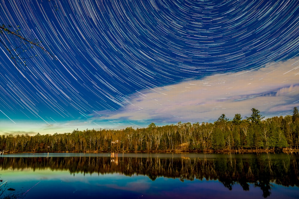 Ein See mit Bäumen und Sternenhimmel darüber