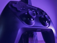 A close-up of a gaming controller illuminated by neon lights.