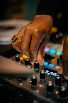 Close-up of DJ equipment with hands adjusting the mixer during a wedding party.