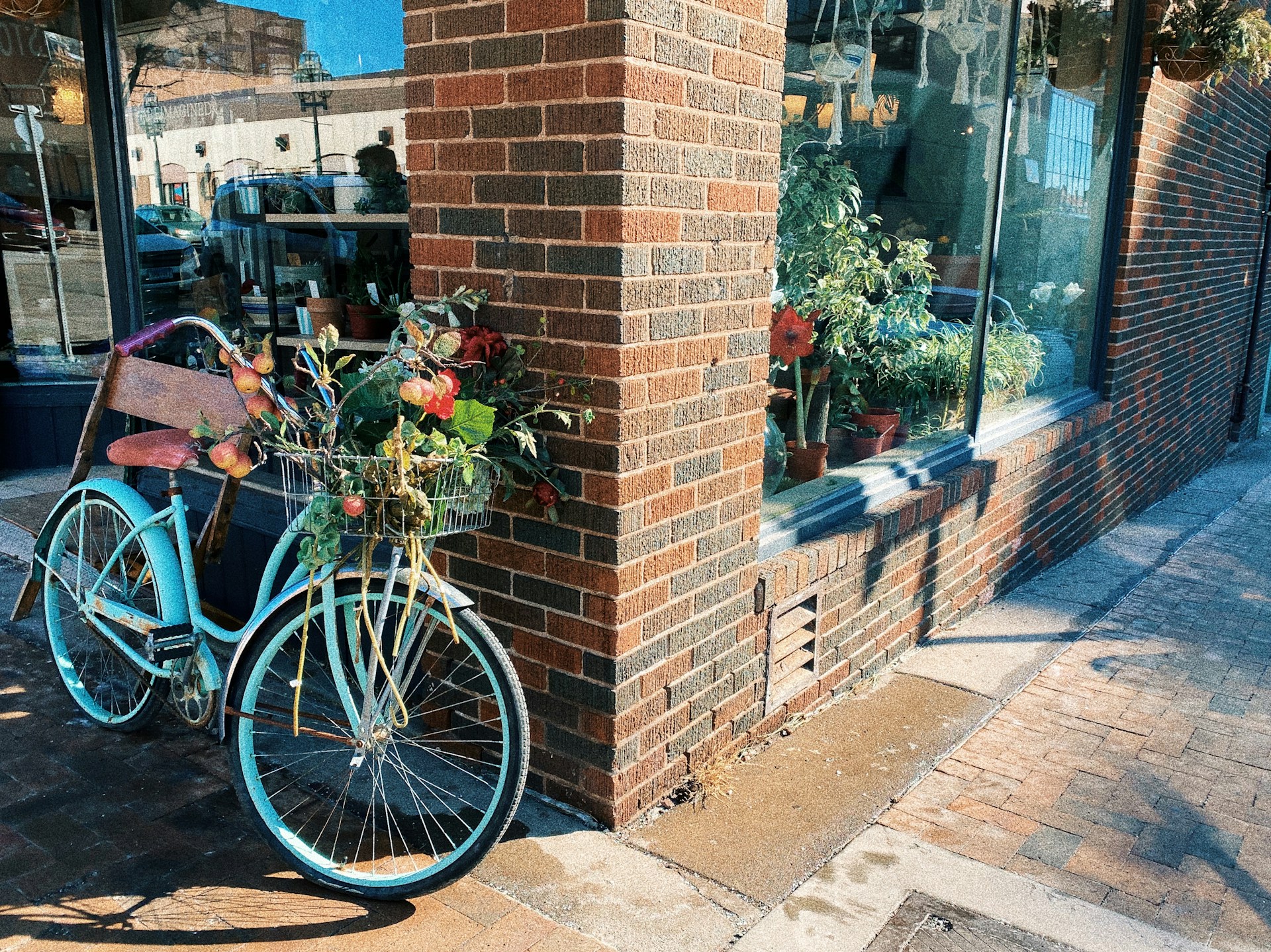 a bicycle parked next to a brick building with a basket of flowers