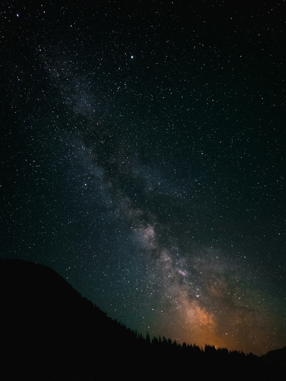 Un cielo nocturno estrellado con una montaña y una colina