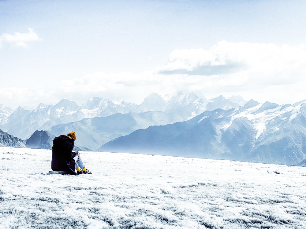 a person and a dog sitting on a snowy mountain