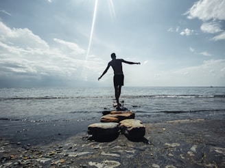 a man standing on a rock on a beach