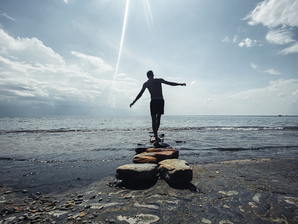 a man standing on a rock on a beach