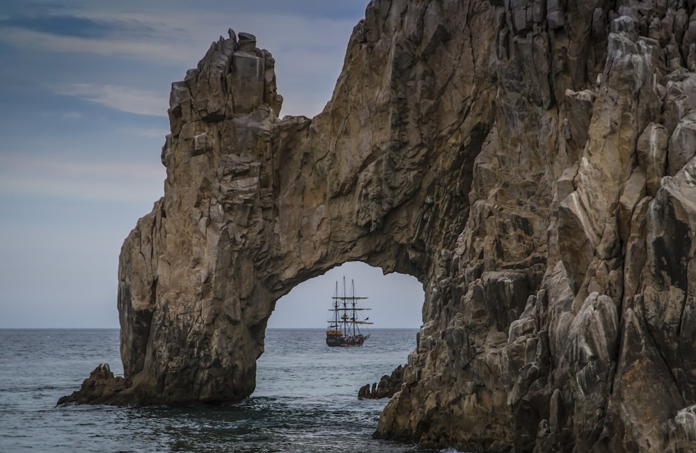 a boat in the water by a rock cliff