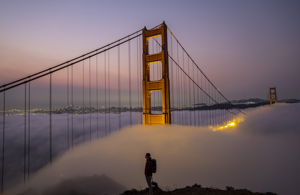 a person standing in front of a large golden bridge